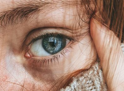 Close-up of a person's eye reflecting a calm, natural scene.